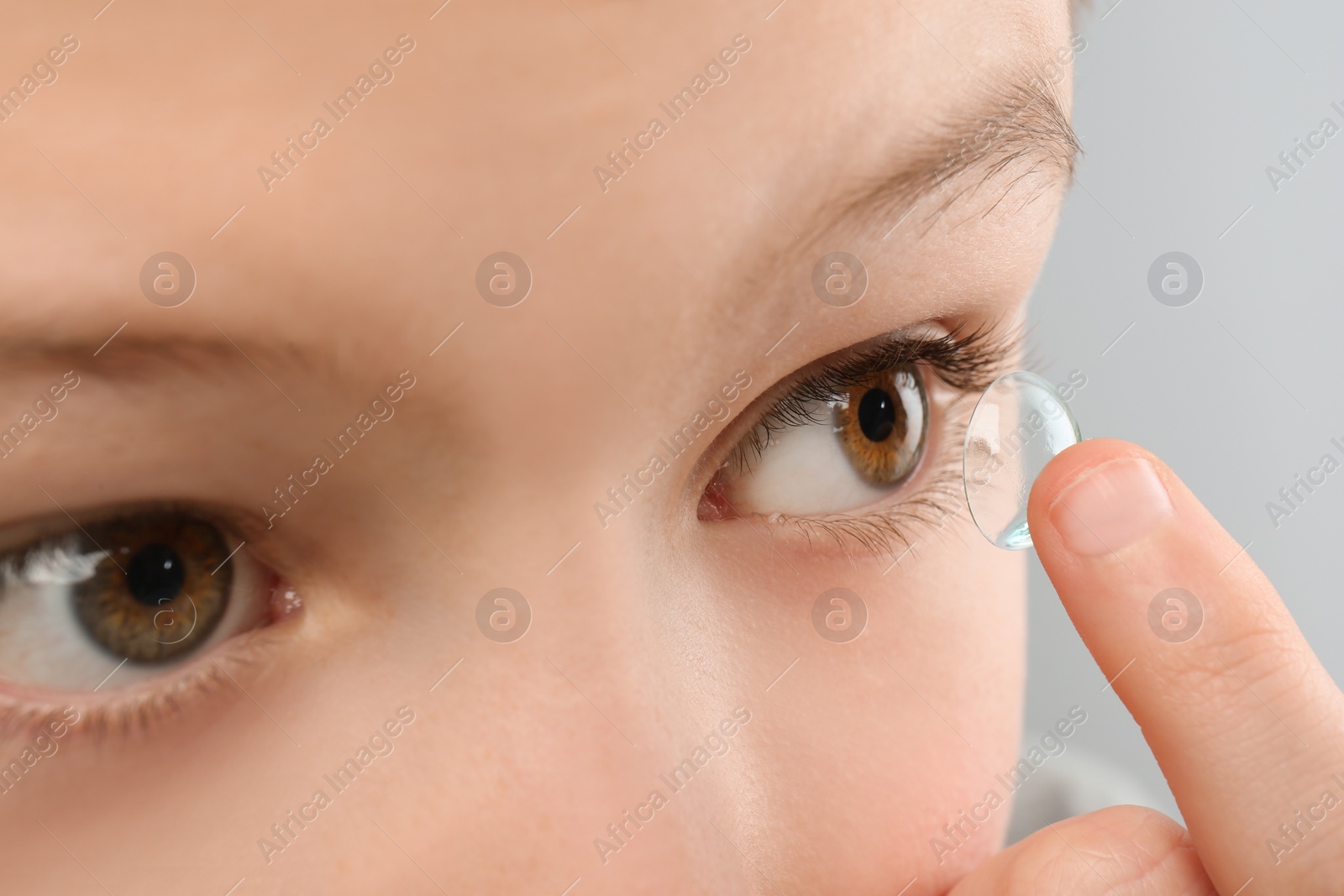 Photo of Little child putting contact lens into his eye, closeup