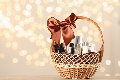 Photo of Wicker basket with cosmetics as present against blurred festive lights. Space for text