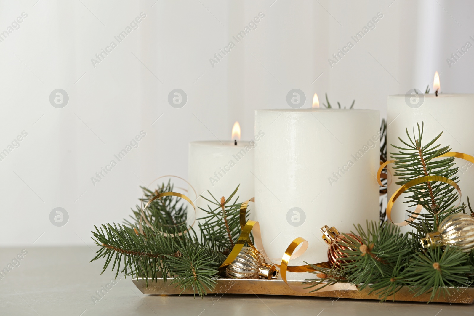 Photo of Beautiful Christmas composition with burning white candles on grey table. Space for text