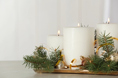 Photo of Beautiful Christmas composition with burning white candles on grey table. Space for text