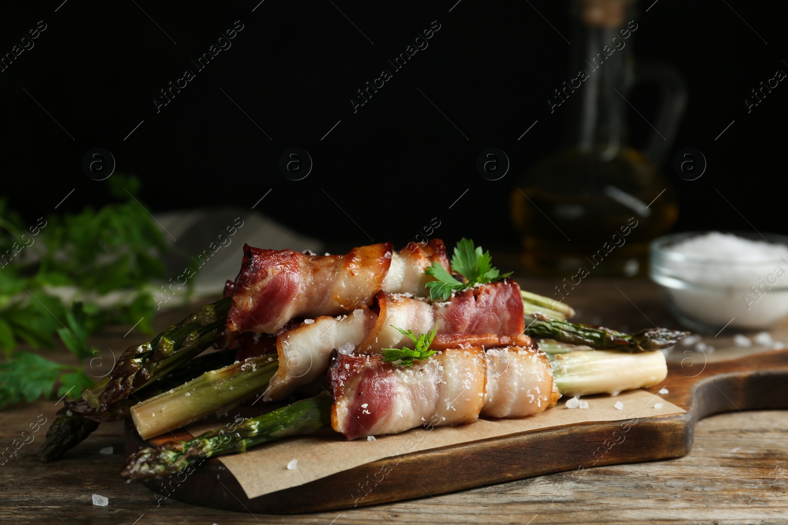 Photo of Oven baked asparagus wrapped with bacon on wooden table