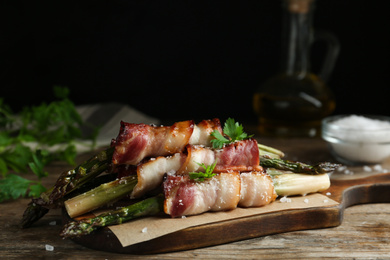 Oven baked asparagus wrapped with bacon on wooden table