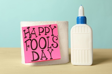 Photo of Toilet paper roll with Happy Fools' Day note and glue on wooden table