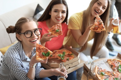 Young people having fun party with delicious pizza indoors