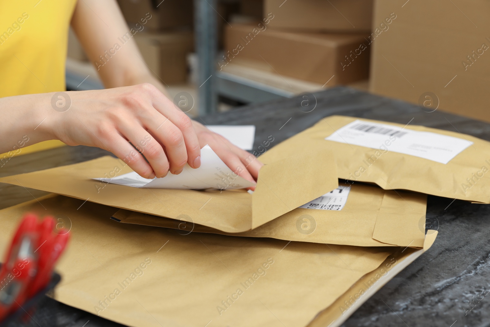 Photo of Post office worker sticking barcode on parcel at counter indoors, closeup