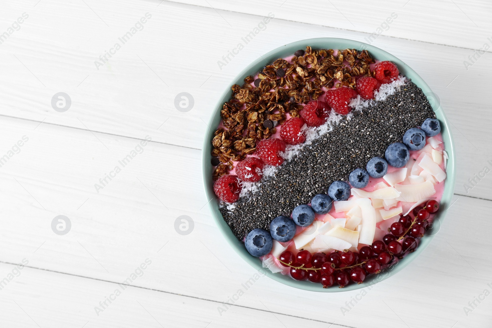 Photo of Tasty smoothie bowl with fresh berries and granola on white wooden table, top view. Space for text