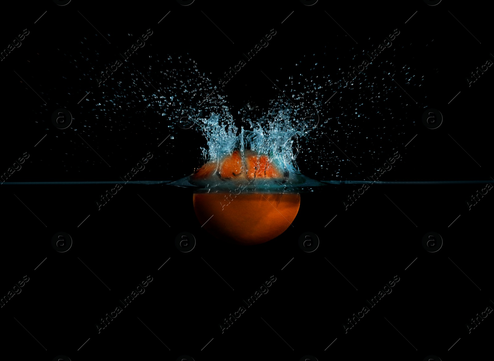 Photo of Grapefruit falling down into clear water against black background