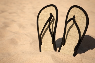 Photo of Flip flops on sandy sea shore. Beach accessory