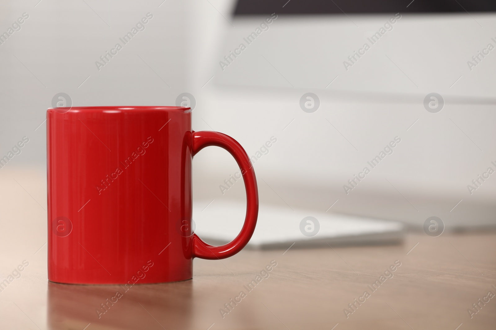 Photo of Red ceramic mug on wooden table at workplace. Space for text