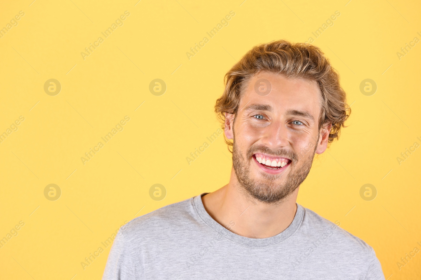 Photo of Handsome young man laughing on color background