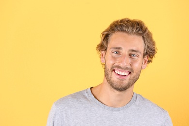 Handsome young man laughing on color background