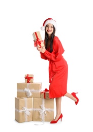 Woman in red dress and Santa hat with Christmas gifts on white background