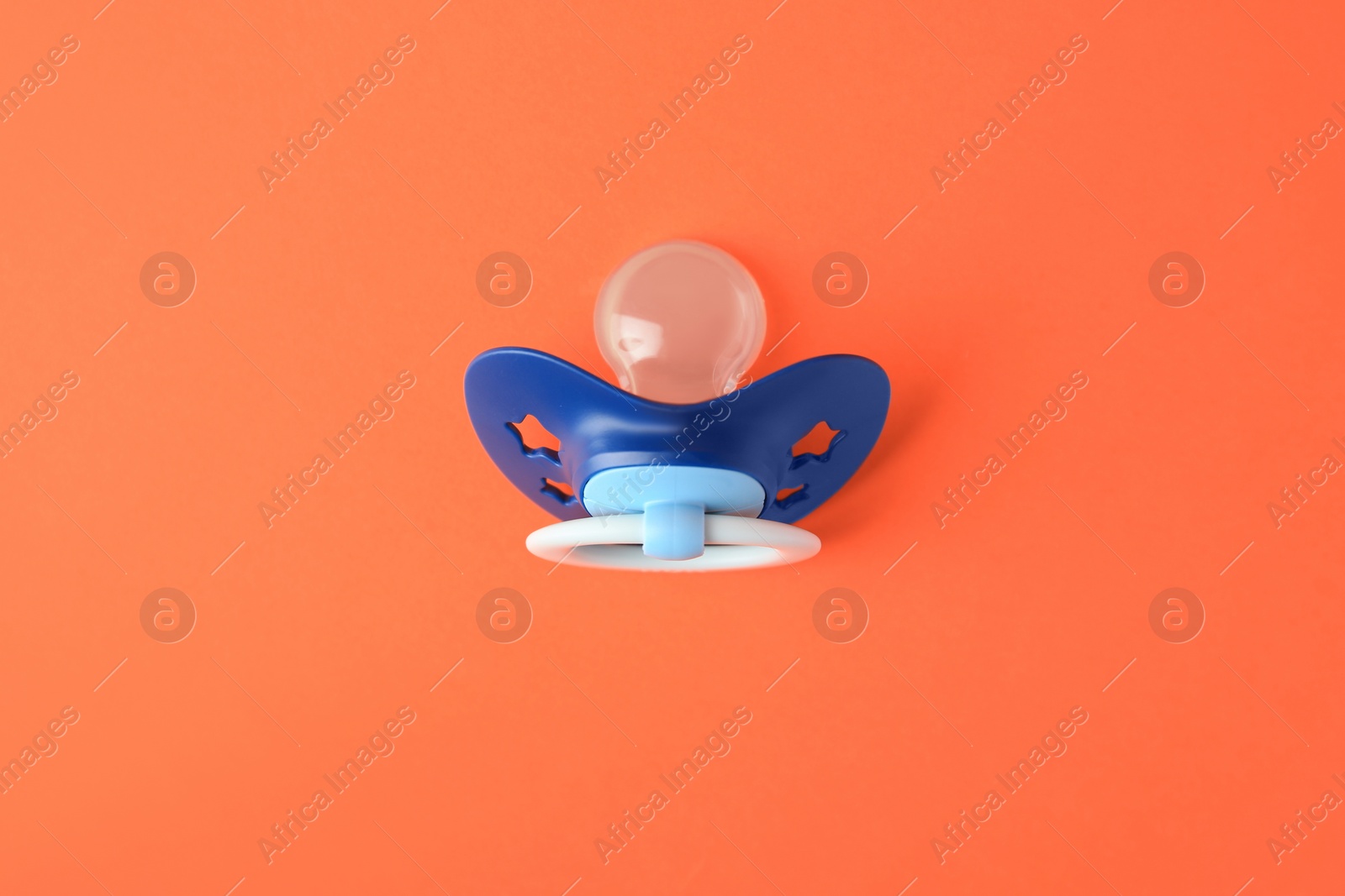 Photo of One blue baby pacifier on orange background, top view