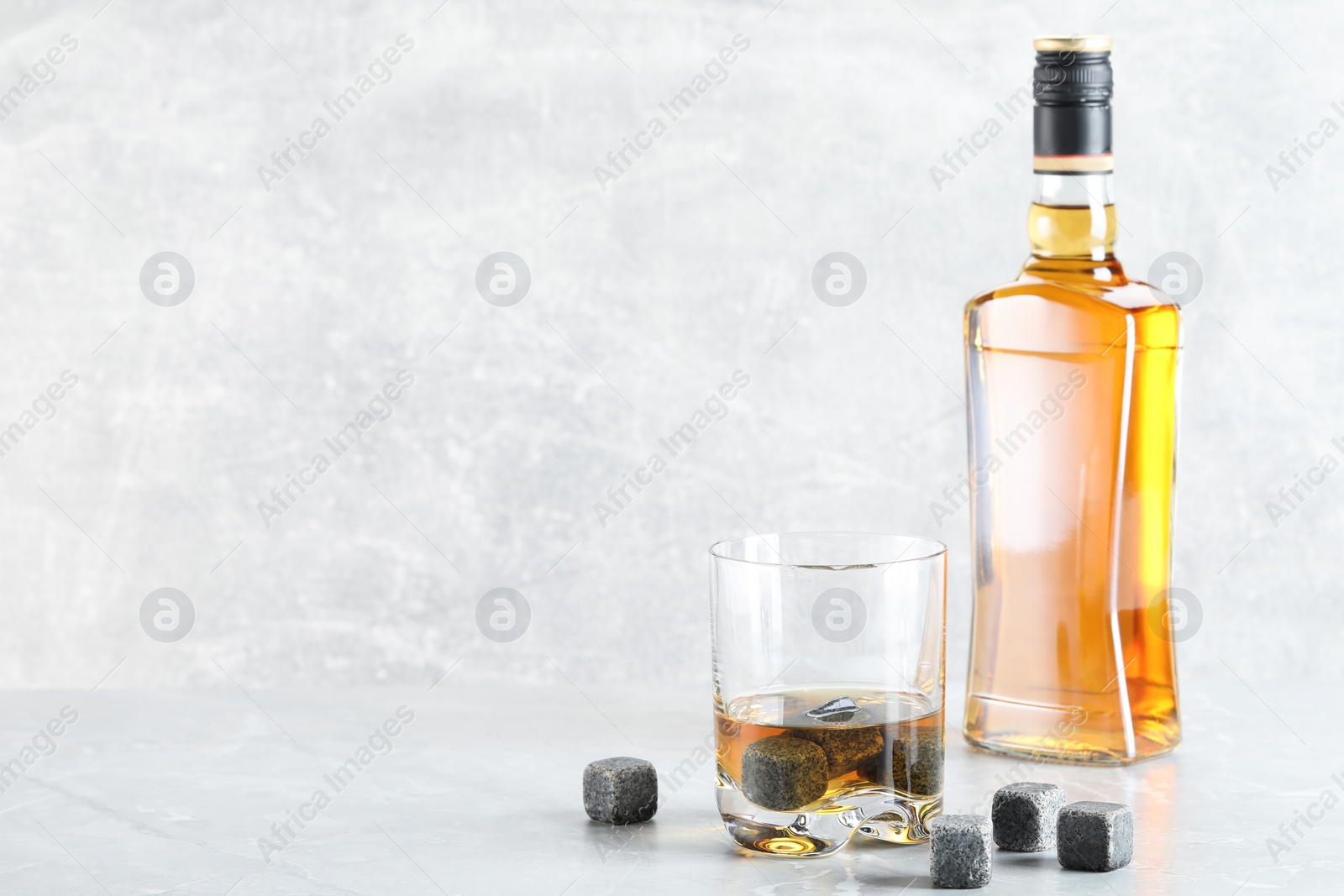 Photo of Whiskey stones and drink on light marble table. Space for text