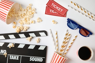 Flat lay composition with clapper, popcorn and tickets on white background. Cinema snack