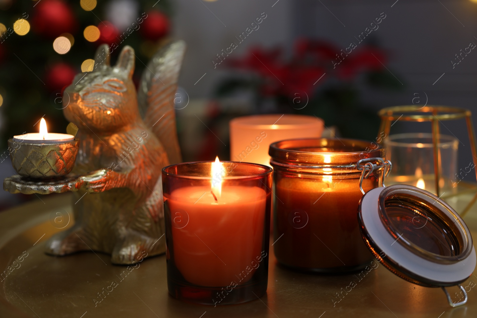 Photo of Burning candles on table in room decorated for Christmas