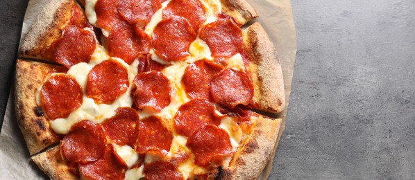 Photo of Tasty pepperoni pizza on grey table, top view. Space for text