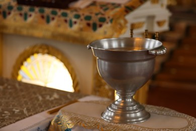 Photo of Silver vessel with holy water on stand in church, space for text. Baptism ceremony