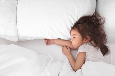 Photo of Cute little girl sleeping in bed, view from above. Space for text