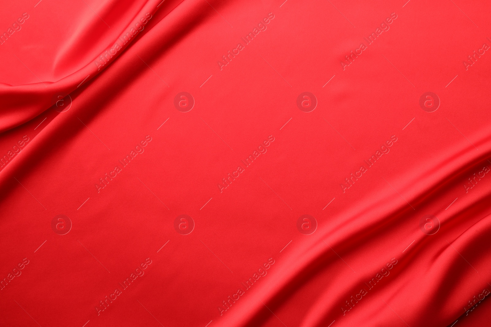 Photo of Crumpled red silk fabric as background, top view. Space for text