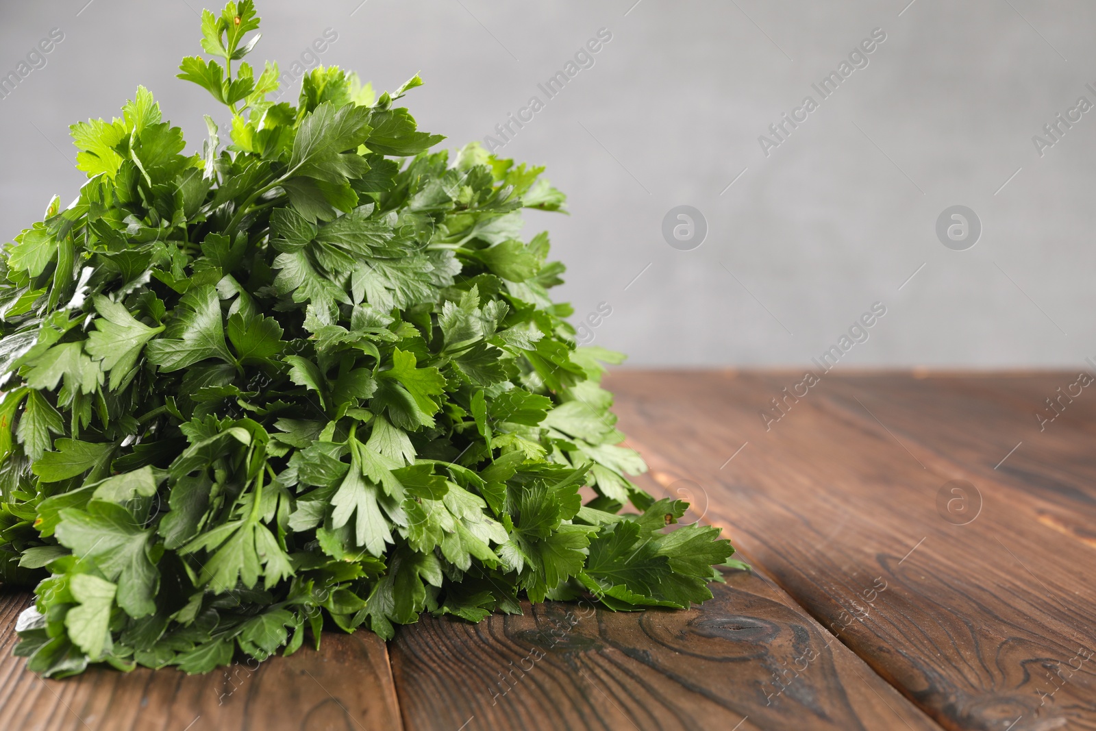 Photo of Bunch of fresh green parsley leaves on wooden table, closeup. Space for text