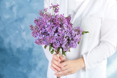 Photo of Young woman holding beautiful blossoming lilac on color background. Spring flowers