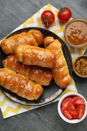 Delicious sausage rolls and ingredients on grey table, flat lay