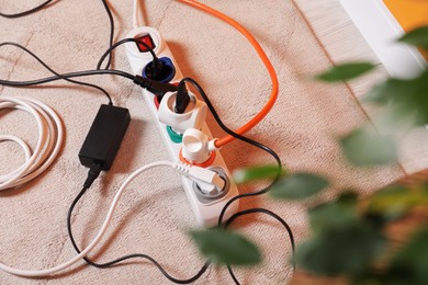 Photo of Power strip with different electrical plugs on white floor indoors