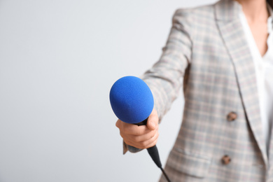 Photo of Journalist with microphone on light background, closeup
