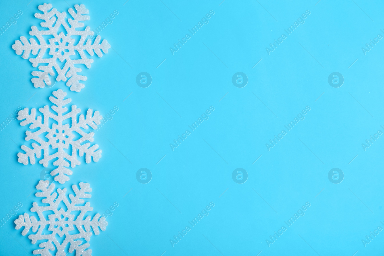 Photo of Beautiful decorative snowflakes on light blue background, flat lay. Space for text