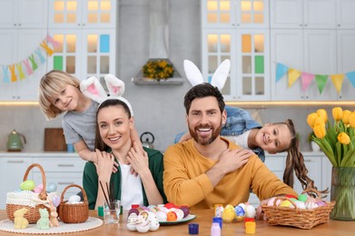 Portrait of happy family and Easter eggs at table in kitchen