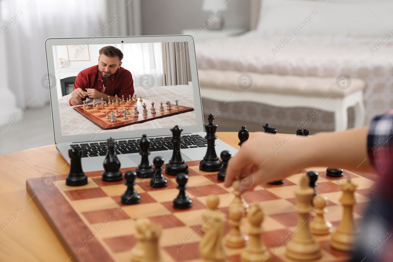 Image of Woman playing chess with partner via online video chat at table indoors, focus on laptop