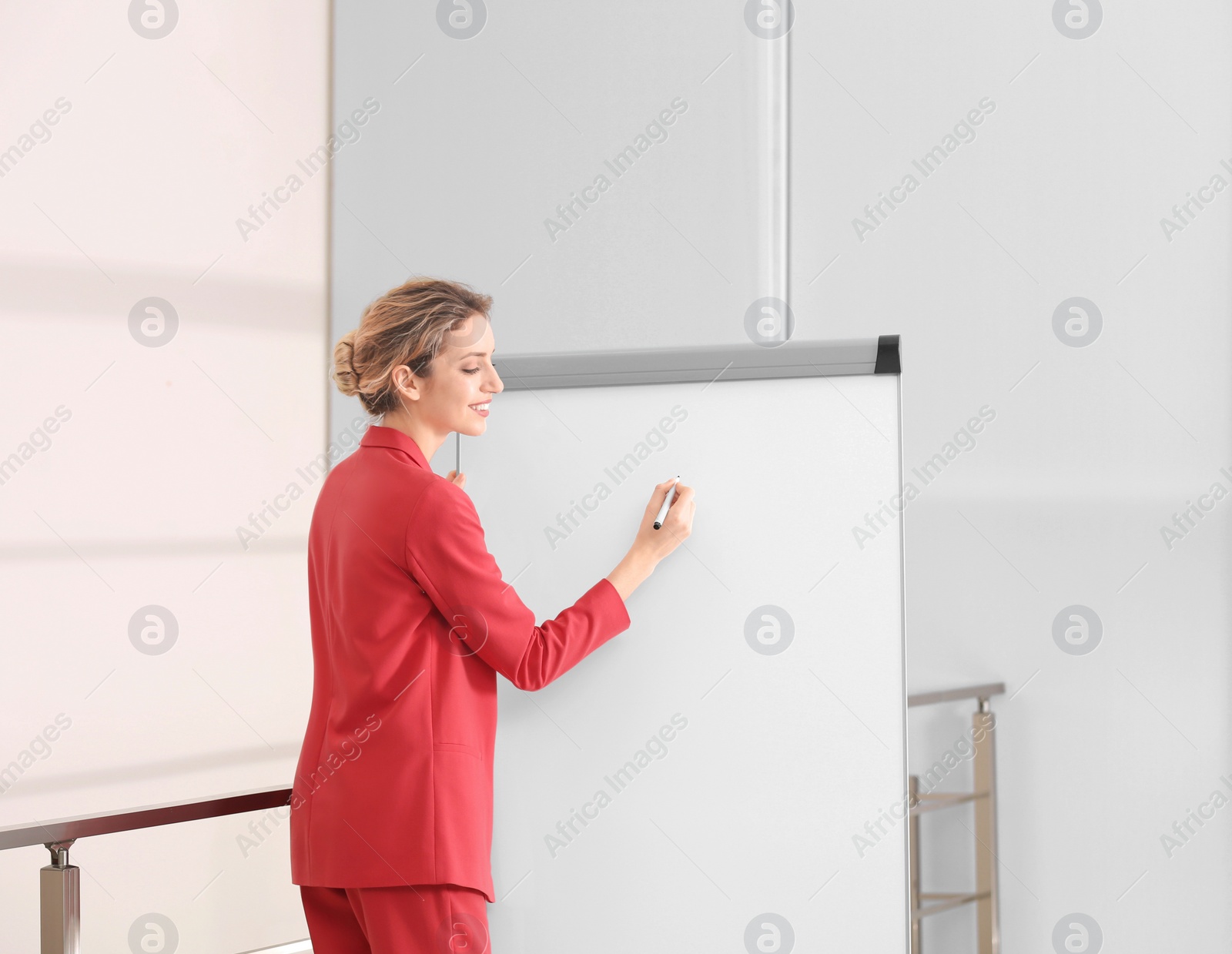 Photo of Female business trainer giving presentation on whiteboard indoors