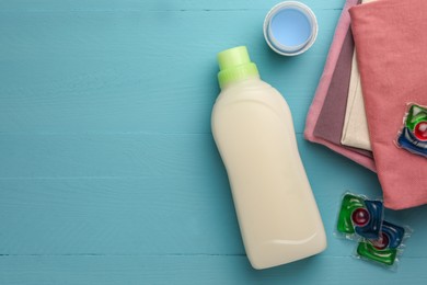 Photo of Flat lay composition with bottle of fabric softener on light blue wooden table. Space for text