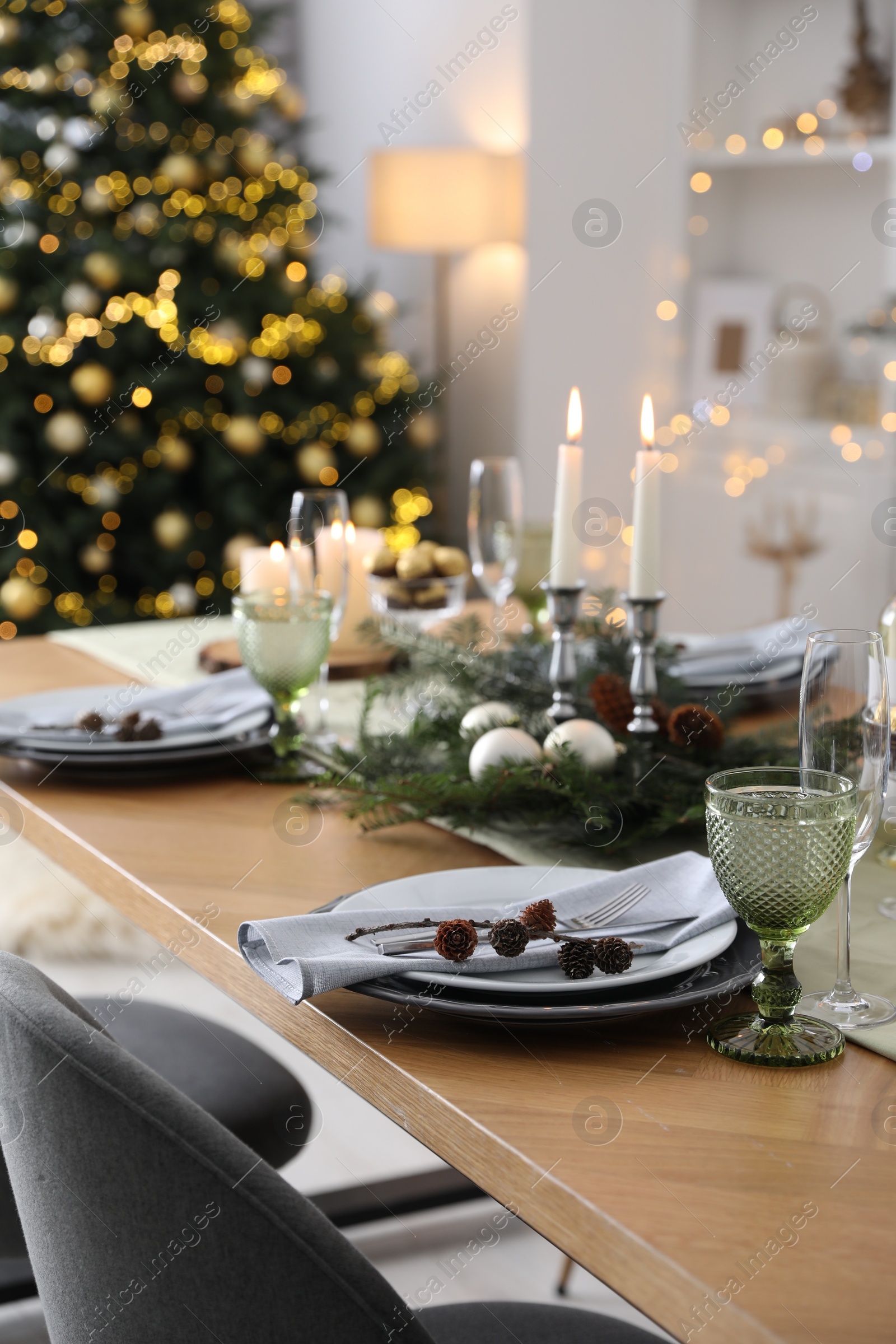 Photo of Christmas table setting with festive decor and dishware in room