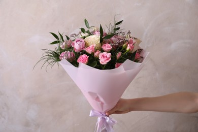 Photo of Woman with bouquet of beautiful roses on beige background, closeup