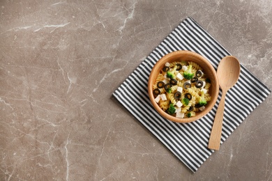 Wooden bowl with delicious pasta primavera on grey background, top view