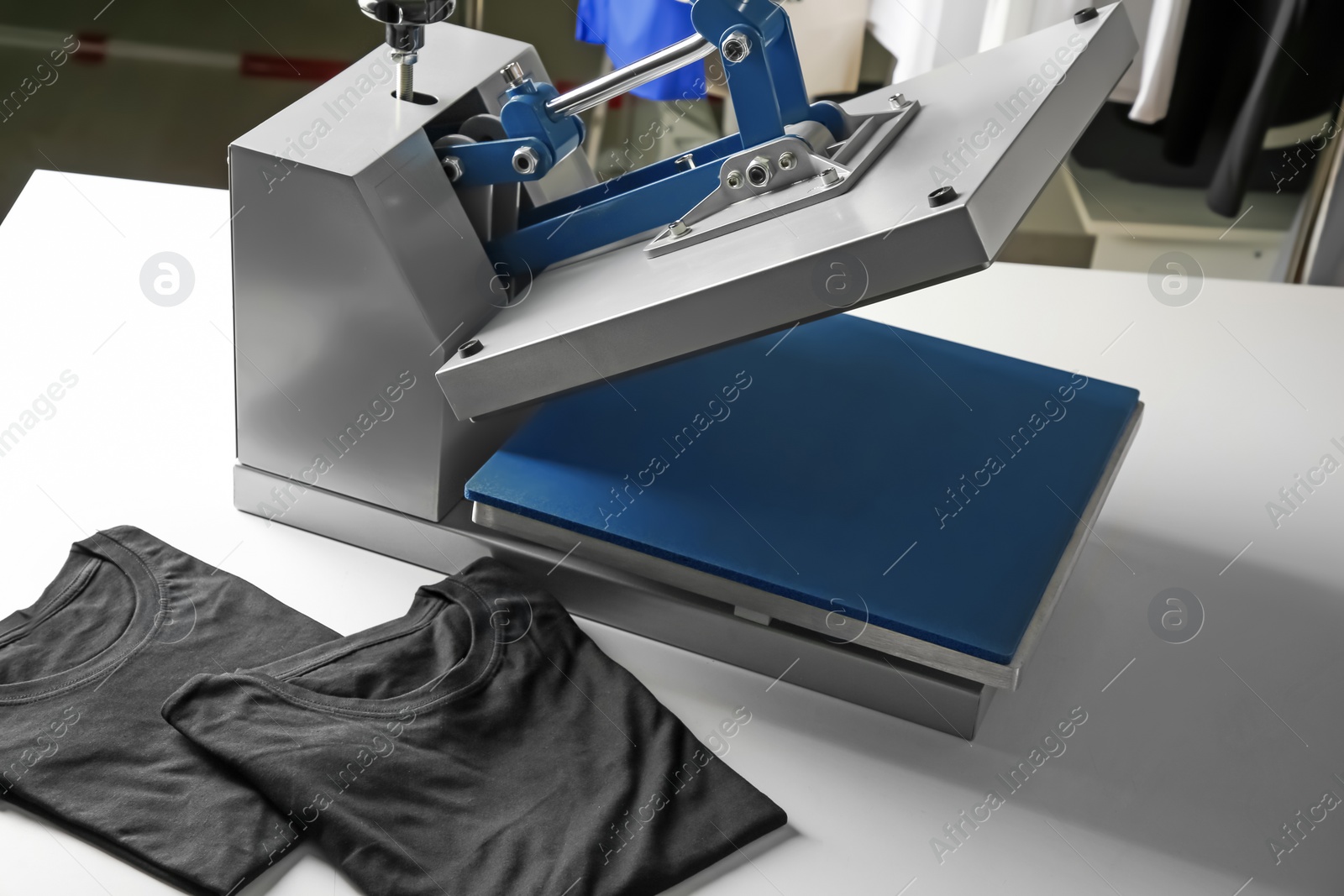 Photo of Printing logo. Heat press and black t-shirt on white table