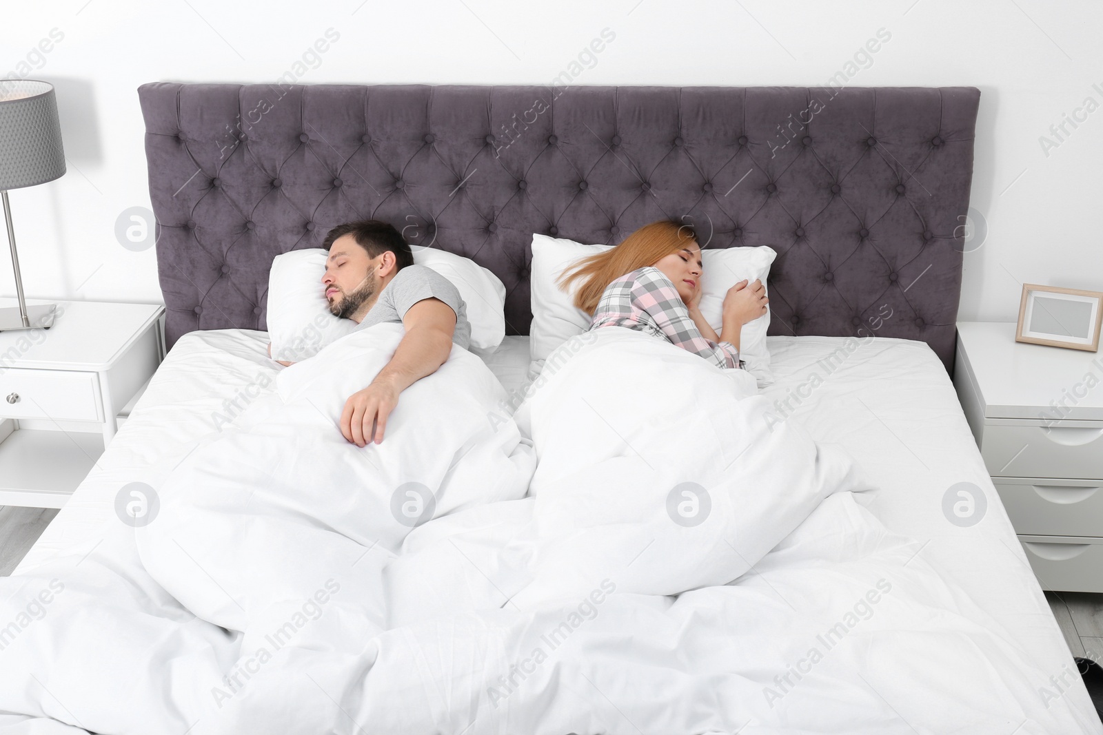 Photo of Couple sleeping back to back in bed at home. Relationship problems