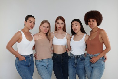 Group of beautiful young women on light grey background