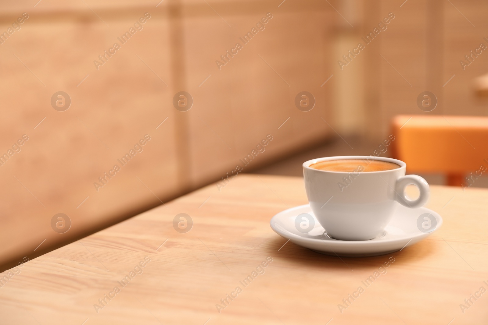 Photo of Cup of fresh aromatic coffee on table against blurred background. Space for text
