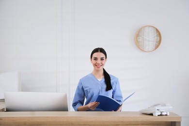 Photo of Receptionist with document case at countertop in hospital