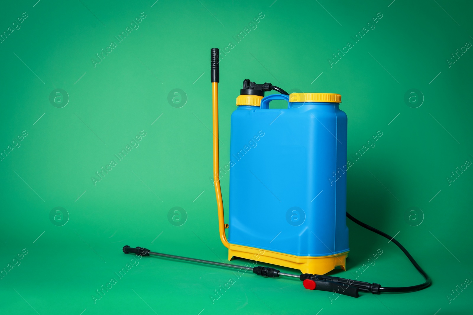 Photo of Manual insecticide sprayer on green background, space for text. Pest control