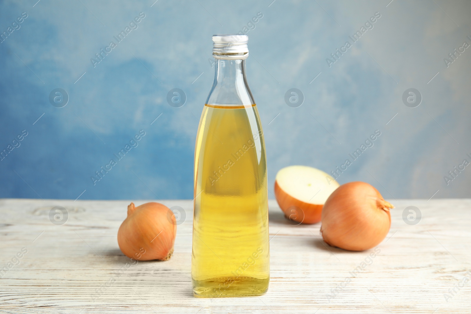 Photo of Glass bottle of onion syrup and fresh vegetable on table