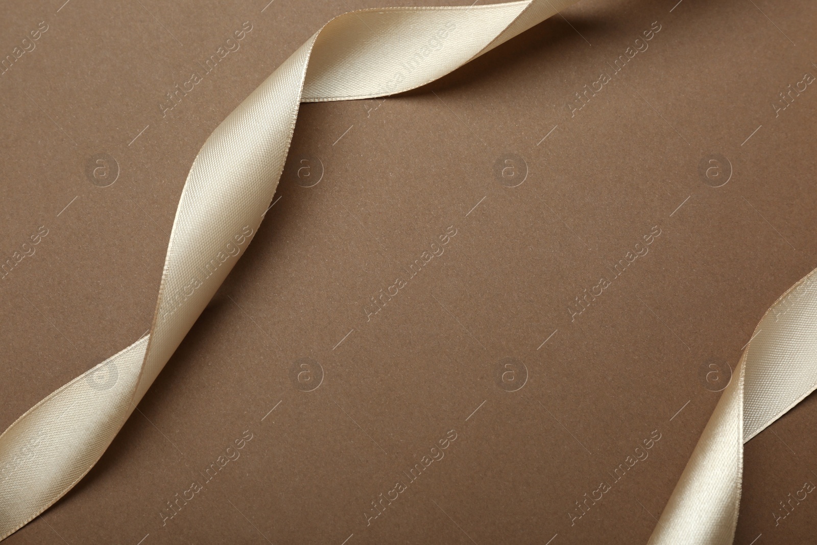 Photo of Beautiful ribbons on brown background, flat lay. Space for text