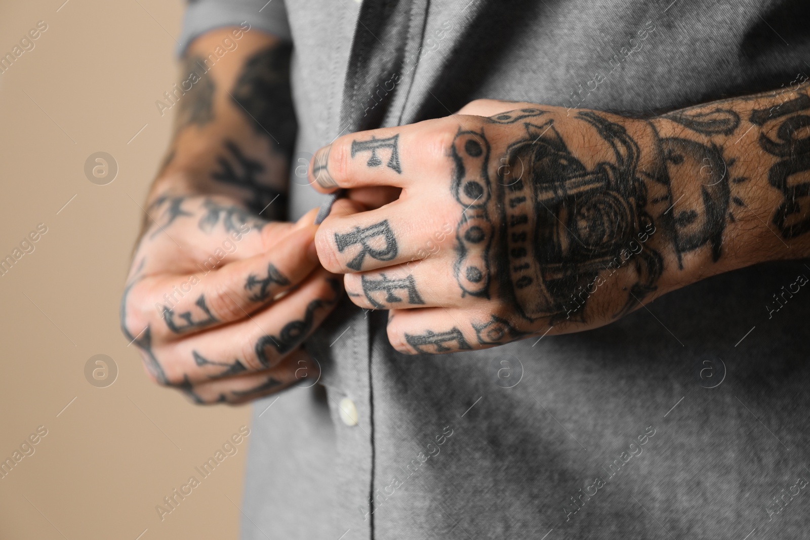 Photo of Young man with tattoos on body against beige background, closeup