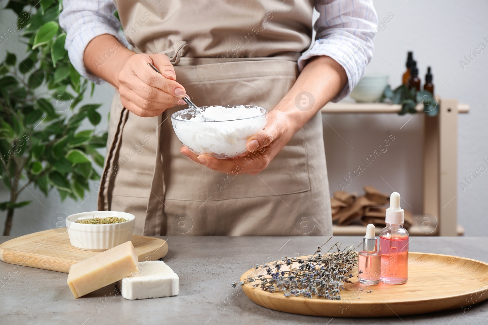 Photo of Woman making natural handmade soap over grey stone table, closeup