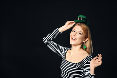 Young woman with green leprechaun hat on black background, space for text. St. Patrick's Day celebration