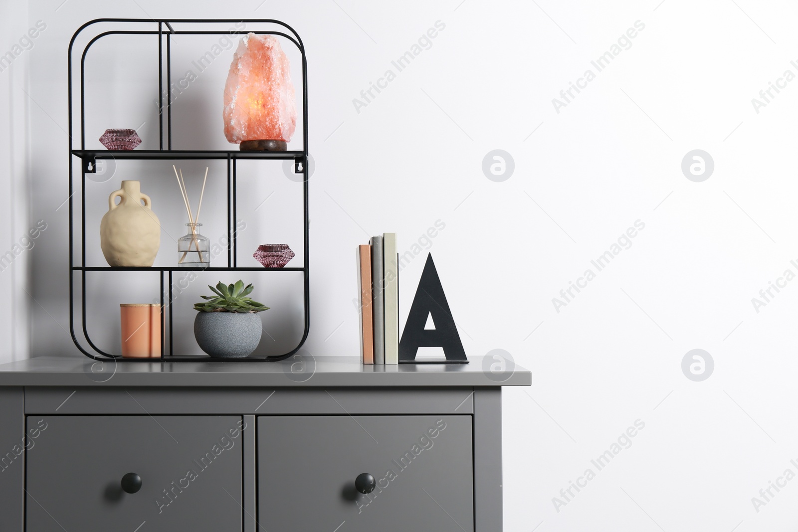 Photo of Shelving unit with decorative elements and books on chest of drawers, space for text. Interior design