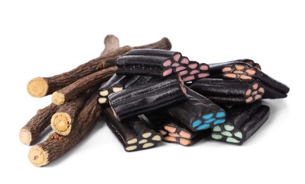 Photo of Many tasty candies and dried sticks of liquorice root isolated on white